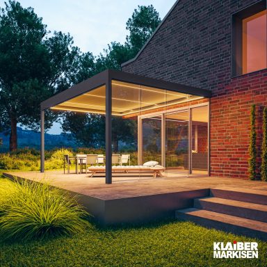 Moderne Terrasse mit Überdachung, Sitzbereich und umgebender Landschaft bei Dämmerung.